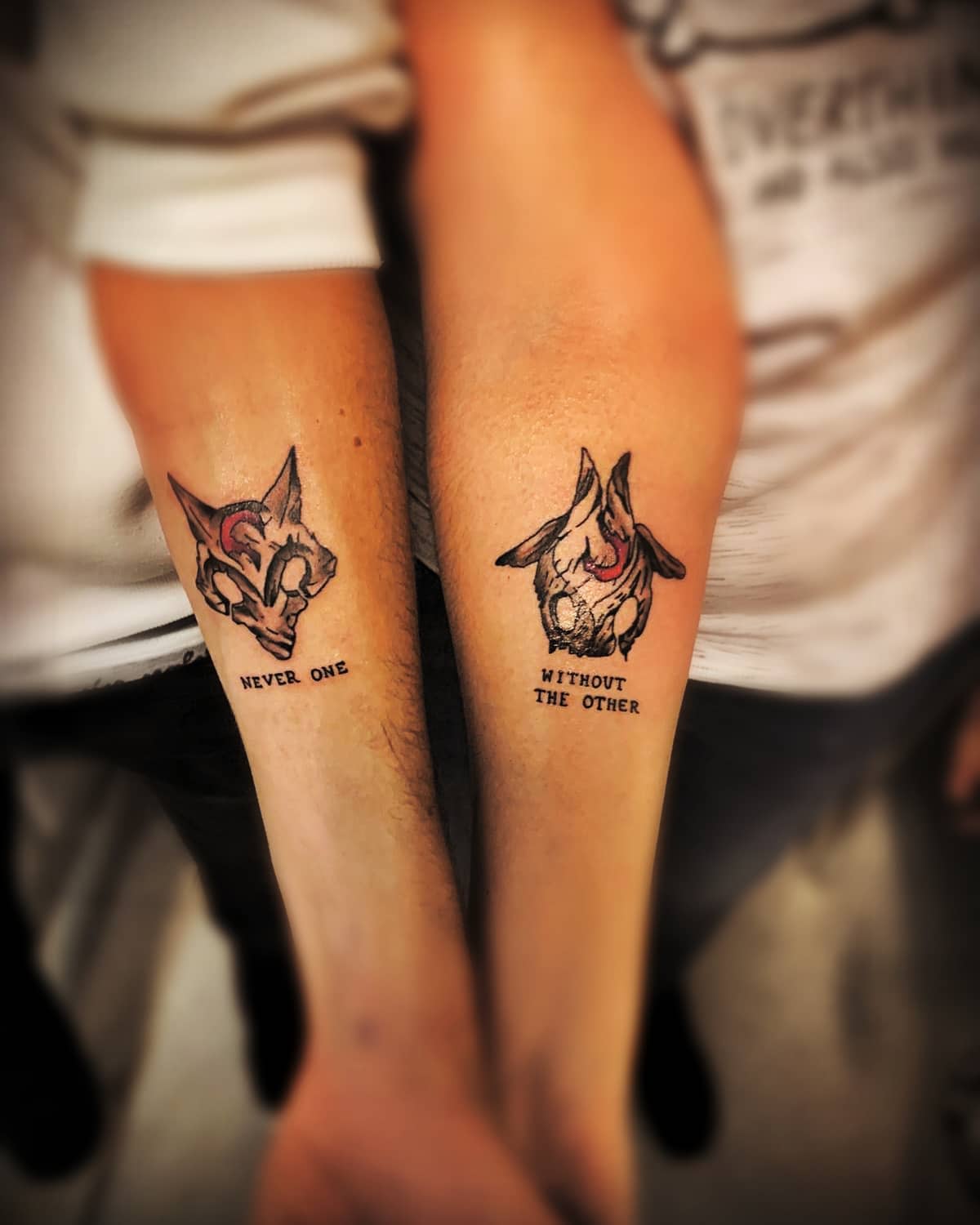 Matching wolf tattoos with the phrases 'NEVER ONE' and 'WITHOUT THE OTHER,' symbolizing unity and inseparable bonds
